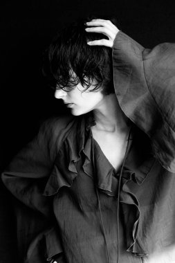 Tek renkli kadın portresi desenli bluz ve el hareketi dramatik kontrastı gösteriyor.