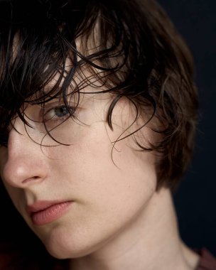 Islak saçlı ve doğal makyajlı saf güzelliği gösteren yakın plan bir kadın portresi.