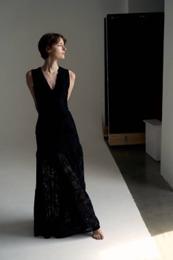 Modern beton mimariye karşı duran sofistike siyah gece elbisesi içinde zarif bir model.