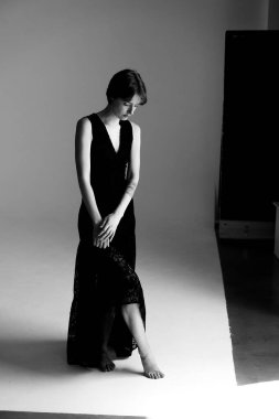 Modern mimari stüdyosunda zarif bir şekilde oturan akışkan siyah akşam giysisi içinde sofistike bir manken.