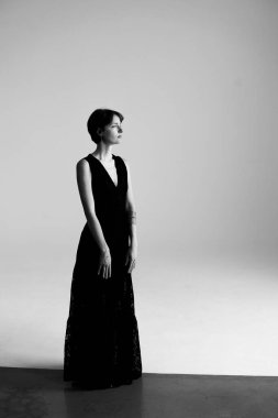 Güzel esmer model modern stüdyo fotoğrafçılığında şık siyah elbise sergiliyor.