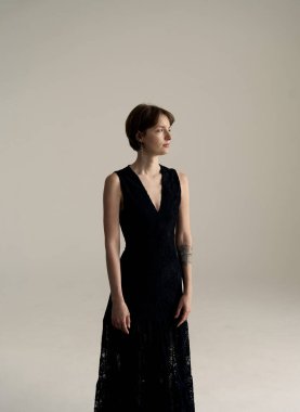 Modern stüdyo ortamında şık siyah gece elbisesi içinde zarif bir şekilde duran sofistike bir model.