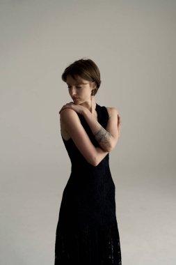 Resim stüdyosunda siyah elbise giymiş güzel bir manken yüzüne nazikçe dokunuyor.