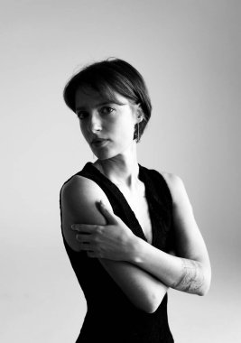 Zarif siyah gece elbisesi içinde şık bir esmer profesyonel stüdyo seansında çapraz kollarla poz veriyor.