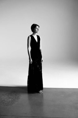 Entellektüel bir kadın, akıcı siyah gece elbisesi içinde, sanatsal gölgelerle birlikte stüdyo fotoğraflarında yer alıyor.