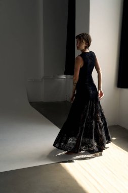 Siyah akşam giyiminde sofistike bir model geometrik ışık desenli çağdaş stüdyo alanında zarif bir poz veriyor.