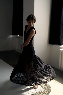 Siyah gece elbisesi içindeki manken dramatik doğal ışık ile modern beton mimariye karşı dinamik bir duruş oluşturur.