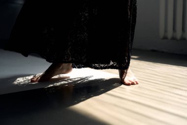 Minimalist odanın güneşli köşesinde pencereden süzülen dramatik ışık geometrik gölge desenleri yaratıyor.