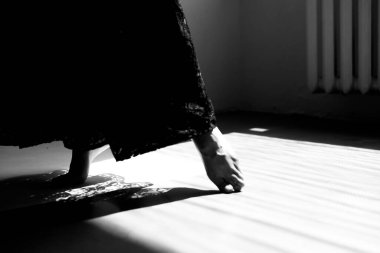 Siyah giysili zarif bir figür. Doğal pencere ışıklandırmasıyla çağdaş parlak bir iç mekânda hareket ediyor.