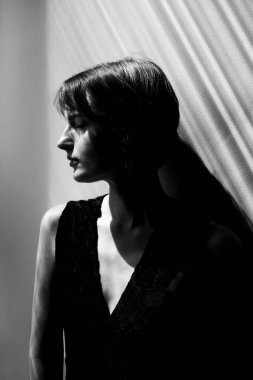 Çağdaş saç stili, zarif siyah bluzlu, profesyonel ışıklandırmalı kendine güvenen kadının stüdyo portresi.