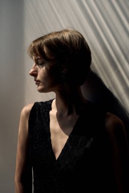 Kısa kahverengi saçlı, siyah kolsuz bluzlu, parlak stüdyo geçmişli bir kadının profesyonel portresi.