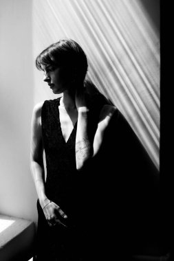 Sanatsal moda portresi zarif siyah elbiseli, güzel doğal pencere ışıklandırmalı bir kadın.