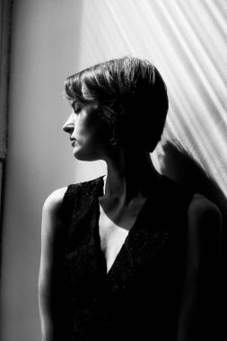 Çağdaş moda portresi, siyah yelekli, dramatik doğal ışıklandırma ve temiz kompozisyonu olan zarif bir kadın.