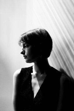 Beyaz arka planda kısa saçlı siyah ceketli bir kadının profesyonel portresi.