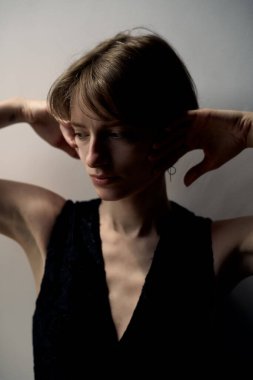 Siyah elbiseli genç kadın saçlarını doğal ışık portresiyle düzeltiyor.