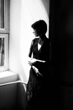 Siyah elbiseli kadının sanatsal portresi. Geniş pencereli, yumuşak doğal ışıklandırmalı.