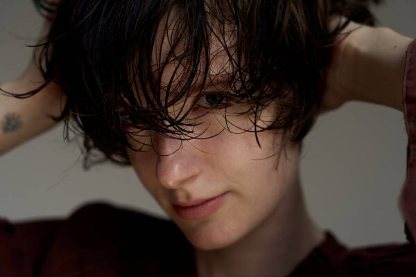 Молодой человек с взъерошенными волосами закрывает глаза в созерцательном драматическом световом портрете