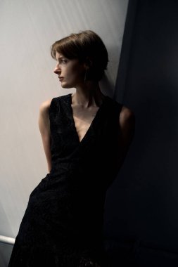 Siyahlı kadının profesyonel portresi. Kısa saçlı, doğal pencere aydınlatmalı.