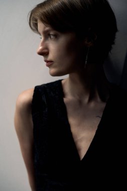 Siyah ceketli, çarpıcı ışıklandırması ve derin düşüncelere dalmış zarif bir genç kadın.