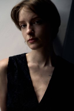 Resmi siyah giysili şık esmer kadın, doğal pencere aydınlatmalı.