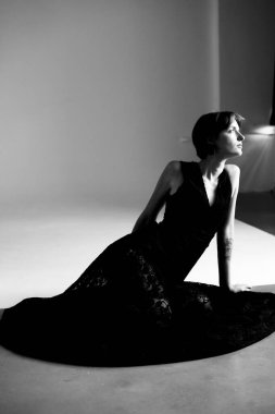 Profesyonel stüdyo portresi, zarif siyah elbiseli, dramatik yan ışıklandırması olan bir kadın.