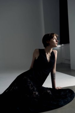 Zarif siyah elbiseli manken profesyonel stüdyo ışıklandırması ile zarif bir pozu yakaladı.