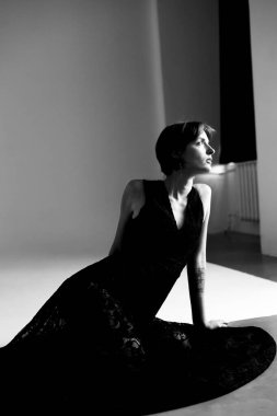 Siyah giyinmiş kadının çağdaş portresi tarafsız arkaplana karşı zarif duruşunu sergiliyor.