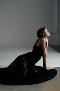 Çağdaş minimalist stüdyo ortamında çekilmiş siyah elbiseli sofistike bir kadın.