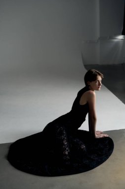 Geometrik stüdyo ışıkları ve gölgelerle sanatsal olarak yerleştirilmiş siyah elbiseli zarif bir manken.