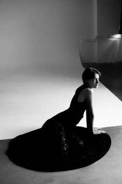 Modern moda portresi, zarif siyah elbiseli, mimari stüdyo arkaplanı olan bir kadın.