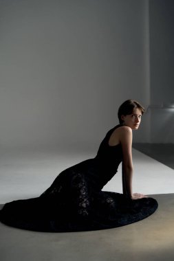 Profesyonel stüdyo ışıklandırması ve geometrik elementleri olan akıcı siyah elbiseli bir kadının dramatik portresi