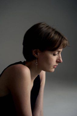 Siyah kolsuz tişörtlü, etkileyici stüdyo ışıklandırmalı genç bir kadının profil portresi