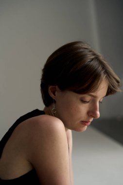 Sakin, siyah kolsuz bluzlu genç bir kadın stüdyo portresini aydınlatırken yakalandı.