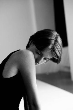 Üzerinde sanatsal gölge oyunu olan siyah-beyaz kolsuz tişörtlü kadın portresi.