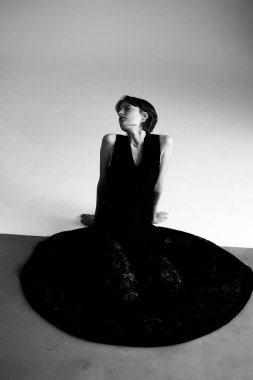 Geometrik gölge çerçevesinde yakalanan siyah elbiseli dansçının tek renkli sanatsal portresi