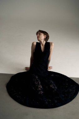 Akan siyah elbiseli zarif kadın dramatik dairesel gölge kompozisyonu içinde zarifçe poz veriyor