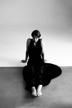 Çarpıcı ışıklandırmayla çağdaş poz vermiş zarif dansçının siyah beyaz portresi.