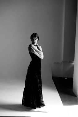 Kolları çapraz, akıcı elbiseli zarif bir kadının tek renkli moda portresi.