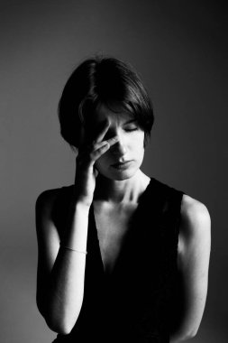 Siyah beyaz, el hareketleriyle yüzünü kapatan kadın portresi.