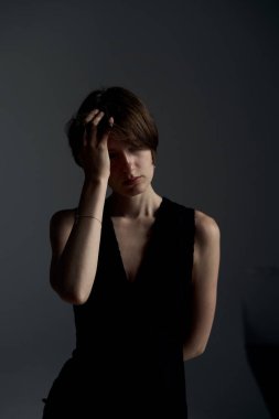 Siyah kolsuz elbiseli zarif esmer kadın profesyonel stüdyo resminde yüz yüze poz veriyor.