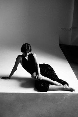 Beyaz açılı bir yüzeye yerleştirilmiş siyah beyaz elbiseli bir kadının çarpıcı, sanatsal fotoğrafı.