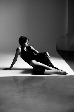 Kadın elbisesinin dramatik siyah beyaz kompozisyonu geometrik platformda heykel silueti oluşturuyor