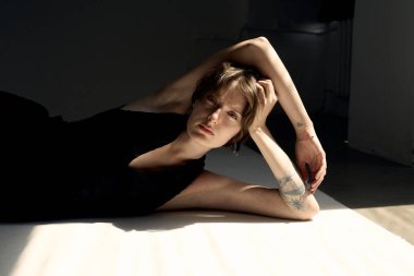 Sanatsal çıplak portre ve sıcak ışıklandırmalı gösterişli kadın zarif bir şekilde oturmuş meditasyon yapıyor.