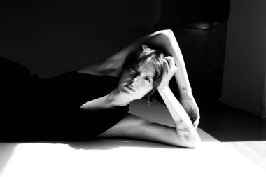 Monokromlu sanatsal çıplak çalışma dramatik ışıklandırmayla zarif düşüncelere dalmış bir kadını yakalıyor.