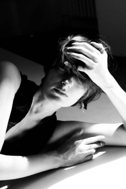 Monokrom sanatsal çıplak çalışma dramatik gölgelerle duygusal dalgın bir kadın görüntüsü yakalamış.