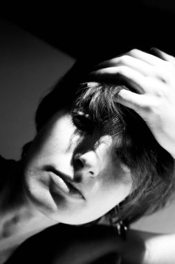 Siyah ve beyaz sanatsal çıplak çalışma dramatik pozlar veren bir kadın sunar.