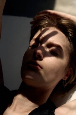 Sıcak ışıklandırmalı sanatsal çıplak portre zarif tefekkür pozisyonunda bir kadını gösteriyor.