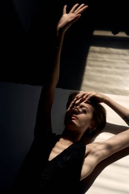 Stüdyo ışıklarıyla dinamik pozlarda kollarını kaldırmış bir kadının sanatsal çıplak portresi.