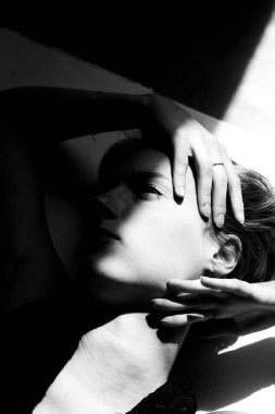 Sanatsal monokrom portresi, kadının tefekküre dayalı ifadesindeki ışık ve gölge arasındaki dramatik zıtlığı gözler önüne seriyor.