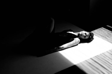 Dramatik pencere aydınlatmalı sanatsal siyah beyaz portre yerde çarpıcı geometrik gölge desenleri oluşturuyor